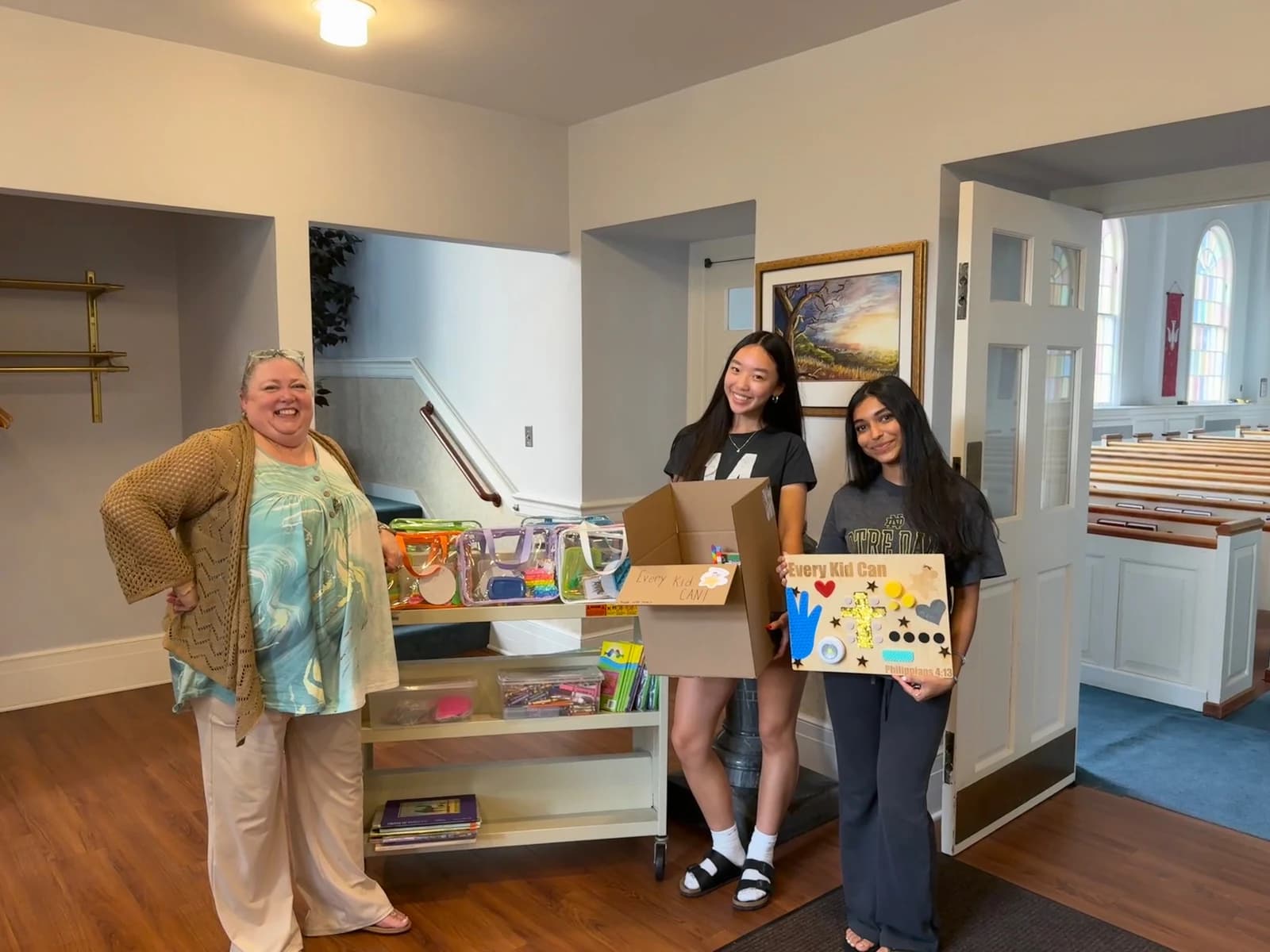 Group displaying sensory boards and donated resources indoors