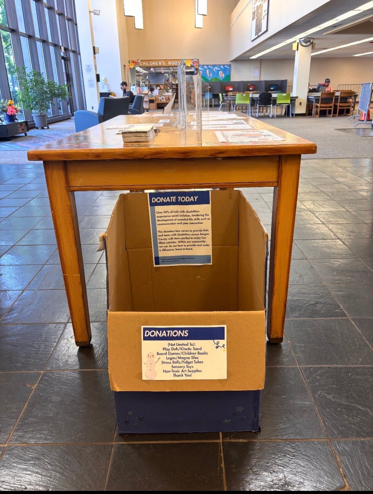 Donation box beneath a wooden table in a library